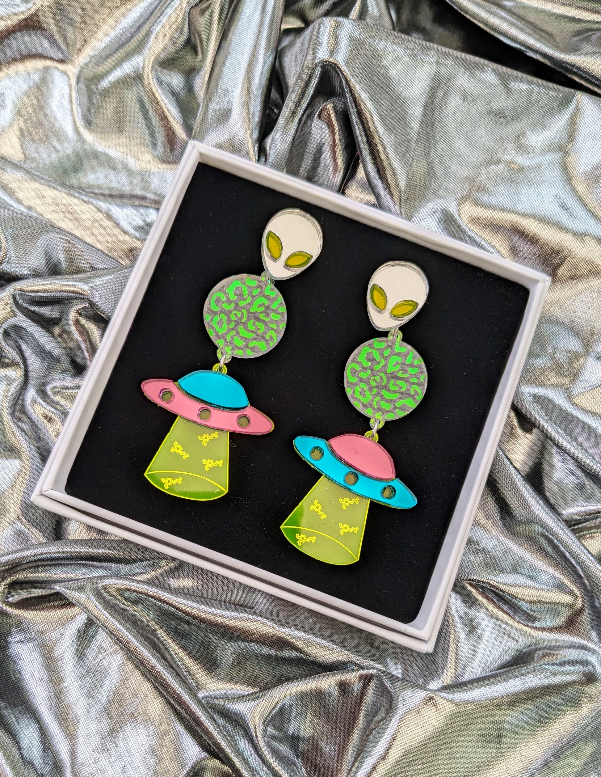 Neon Dopamine Statement Earrings with Pink and Turquoise Mirrored Acrylic Spaceship, a transparent planet with iridescent mermaid acrylic leopard print detailing, a silver mirrored and neon acrylic Alien and neon green acrylic with Dopamine Molecule engravings.