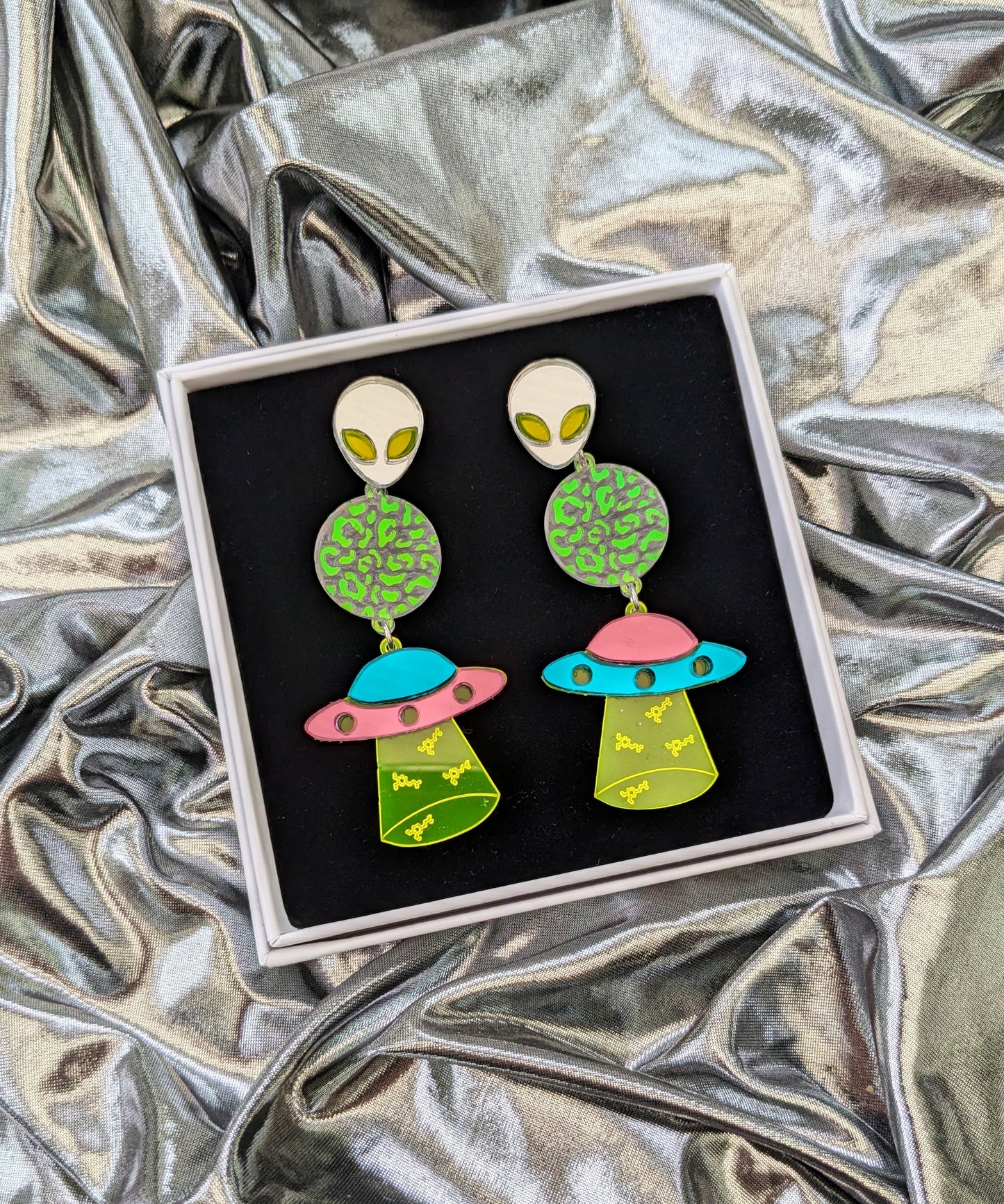 Neon Dopamine Statement Earrings with Pink and Turquoise Mirrored Acrylic Spaceship, a transparent planet with iridescent mermaid acrylic leopard print detailing, a silver mirrored and neon acrylic Alien and neon green acrylic with Dopamine Molecule engravings.