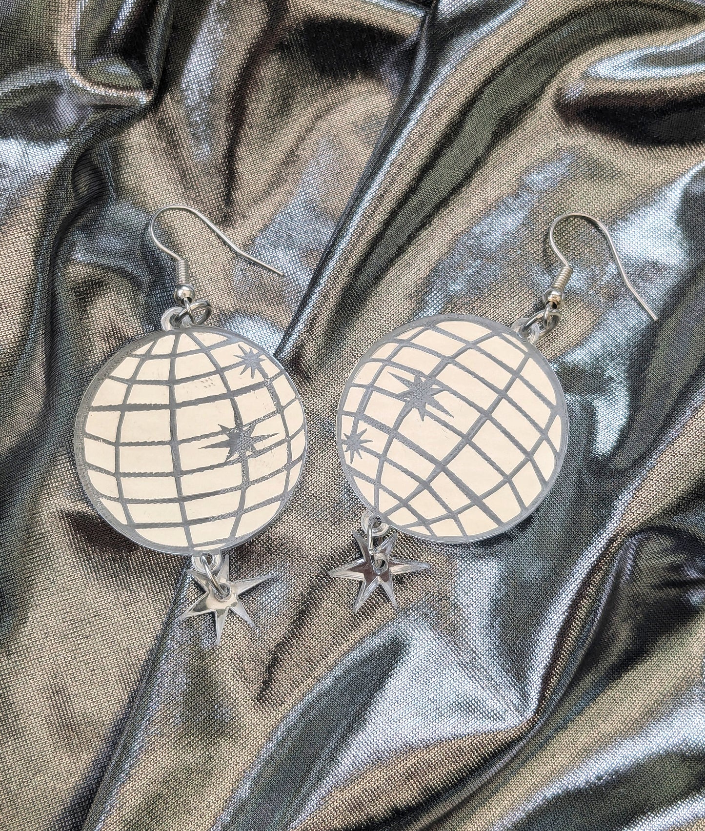 Acrylic mirror effect disco ball earrings on a silver fabric background