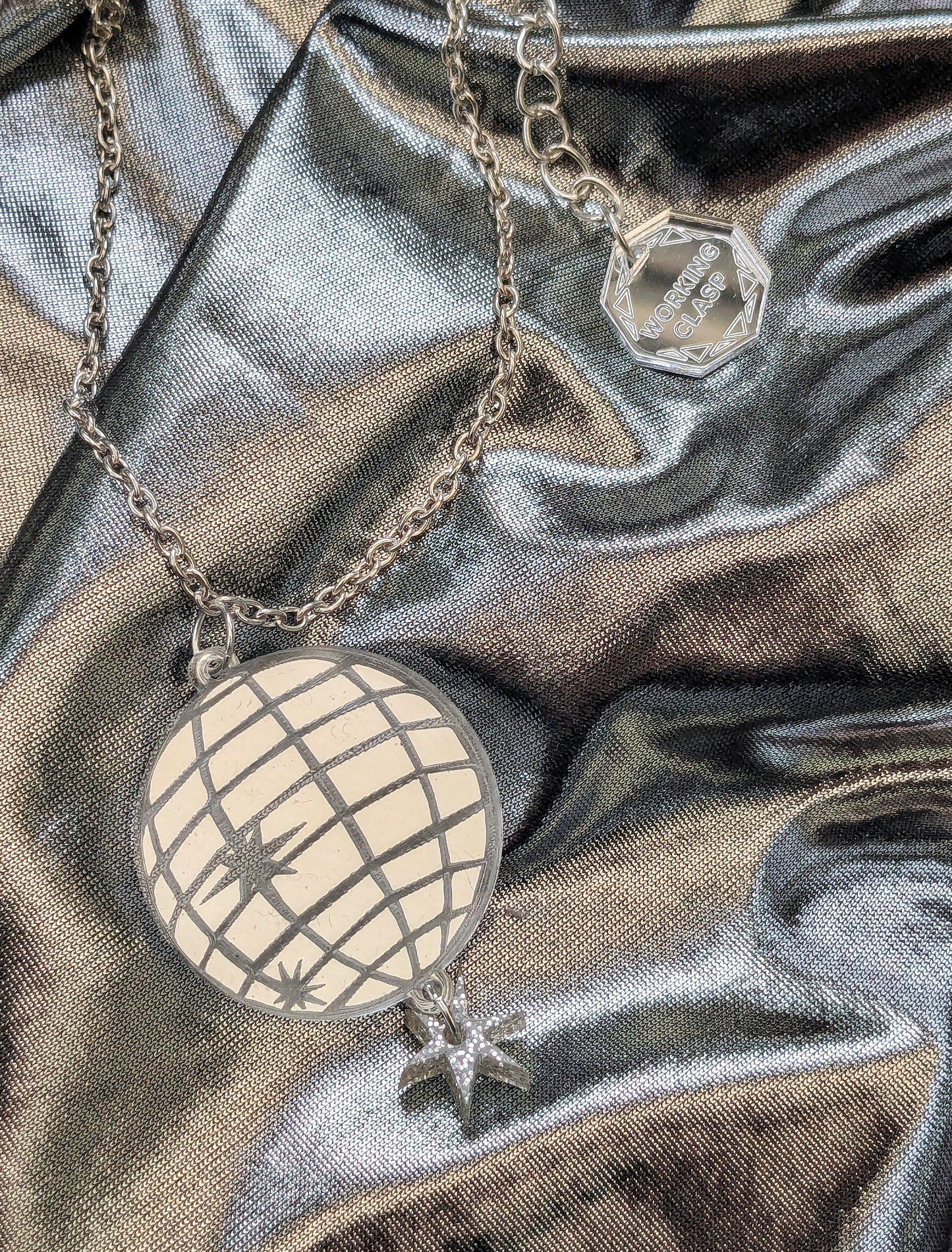 Silver disco ball necklace on silver fabric background