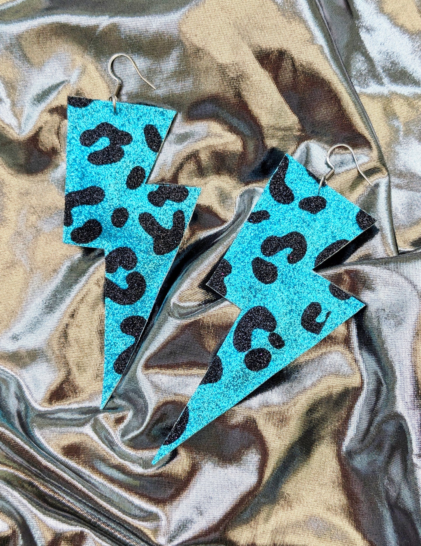 Large leopard print lightning bolt earrings in turquoise and black glitter