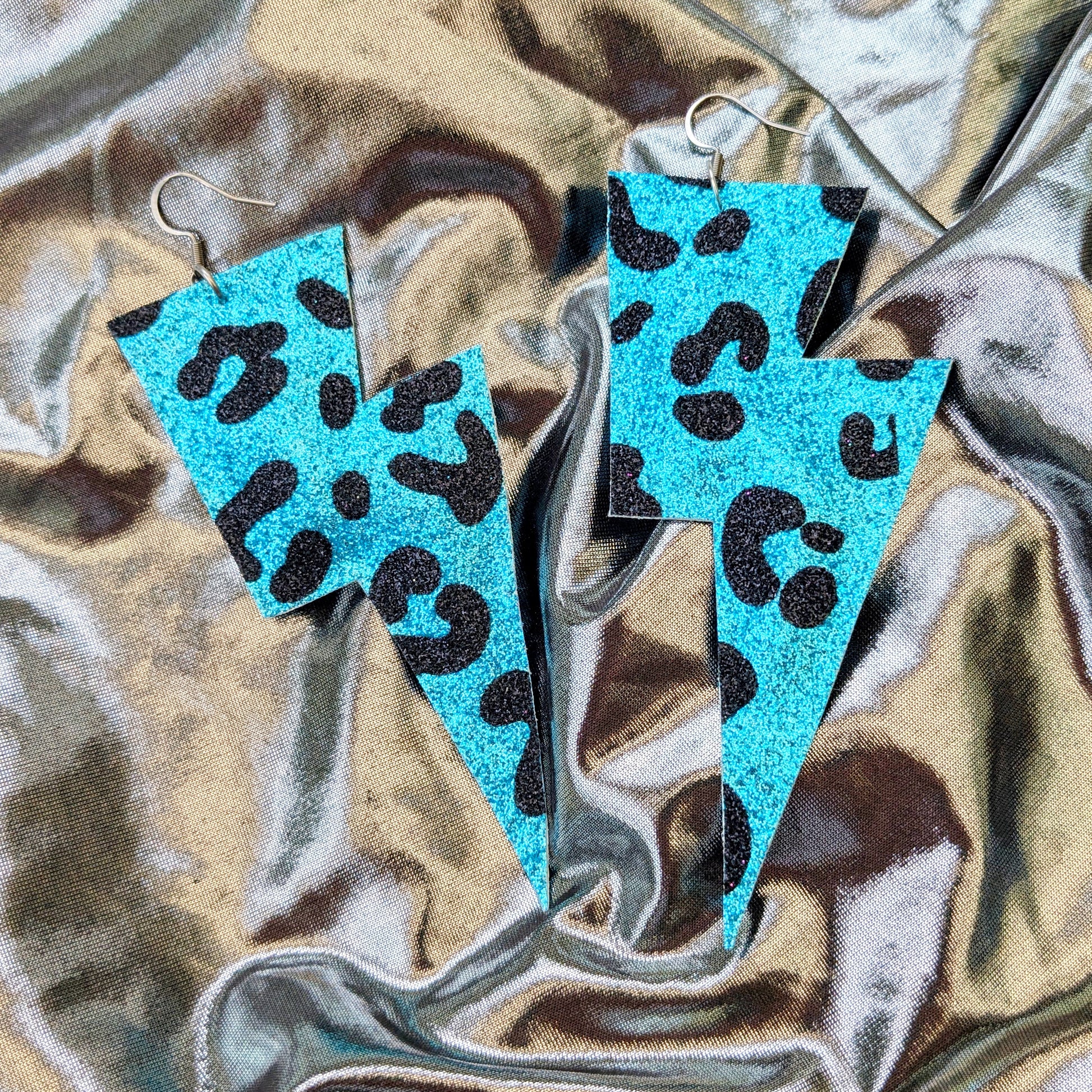 Large leopard print lightning bolt earrings in turquoise and black glitter