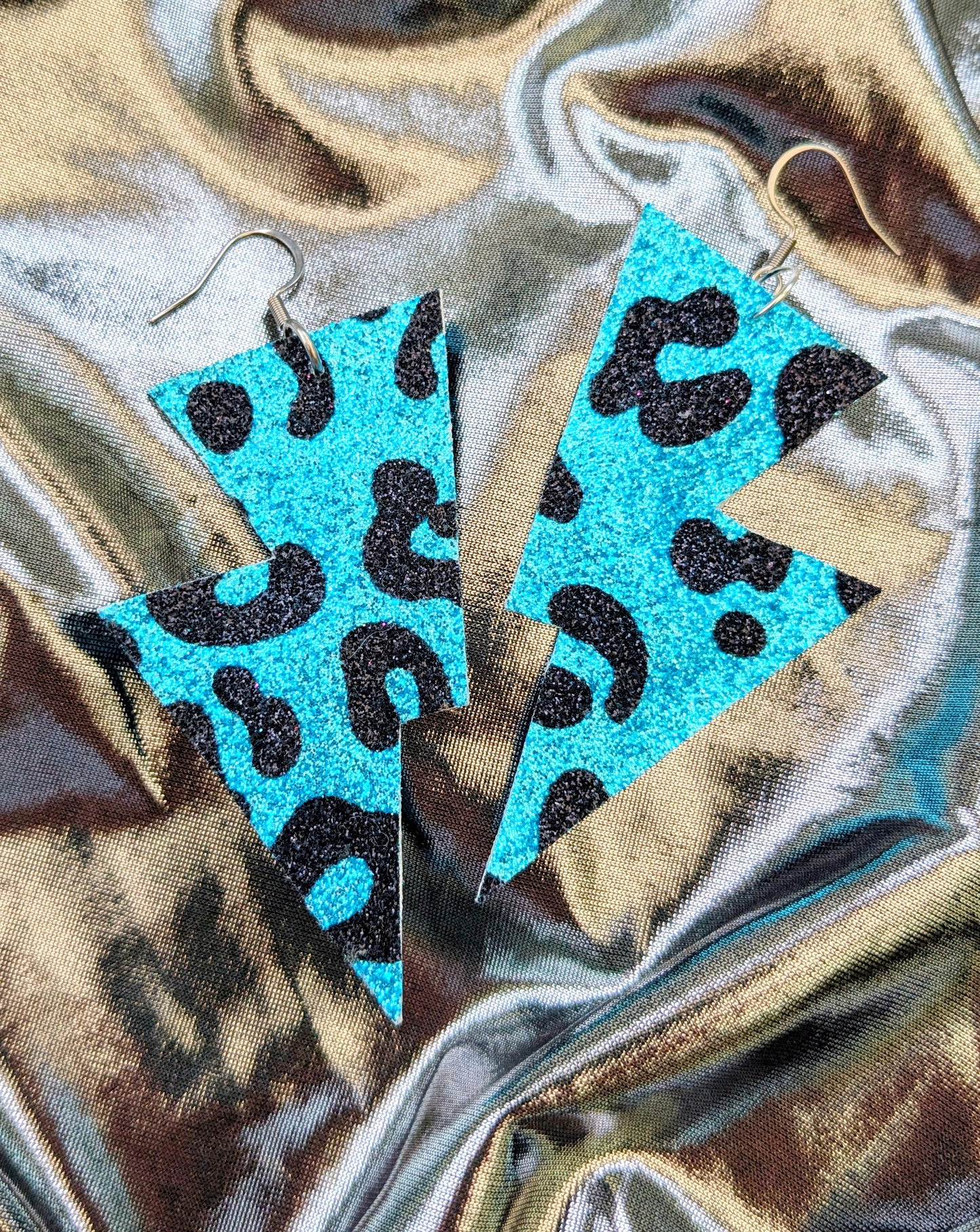 Medium leopard print lightning bolt earrings in turquoise and black glitter fabric