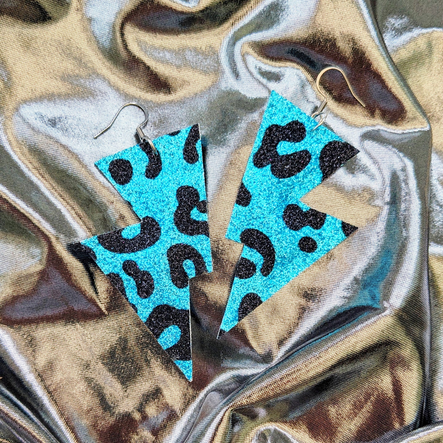 Medium leopard print lightning bolt earrings in turquoise and black glitter fabric