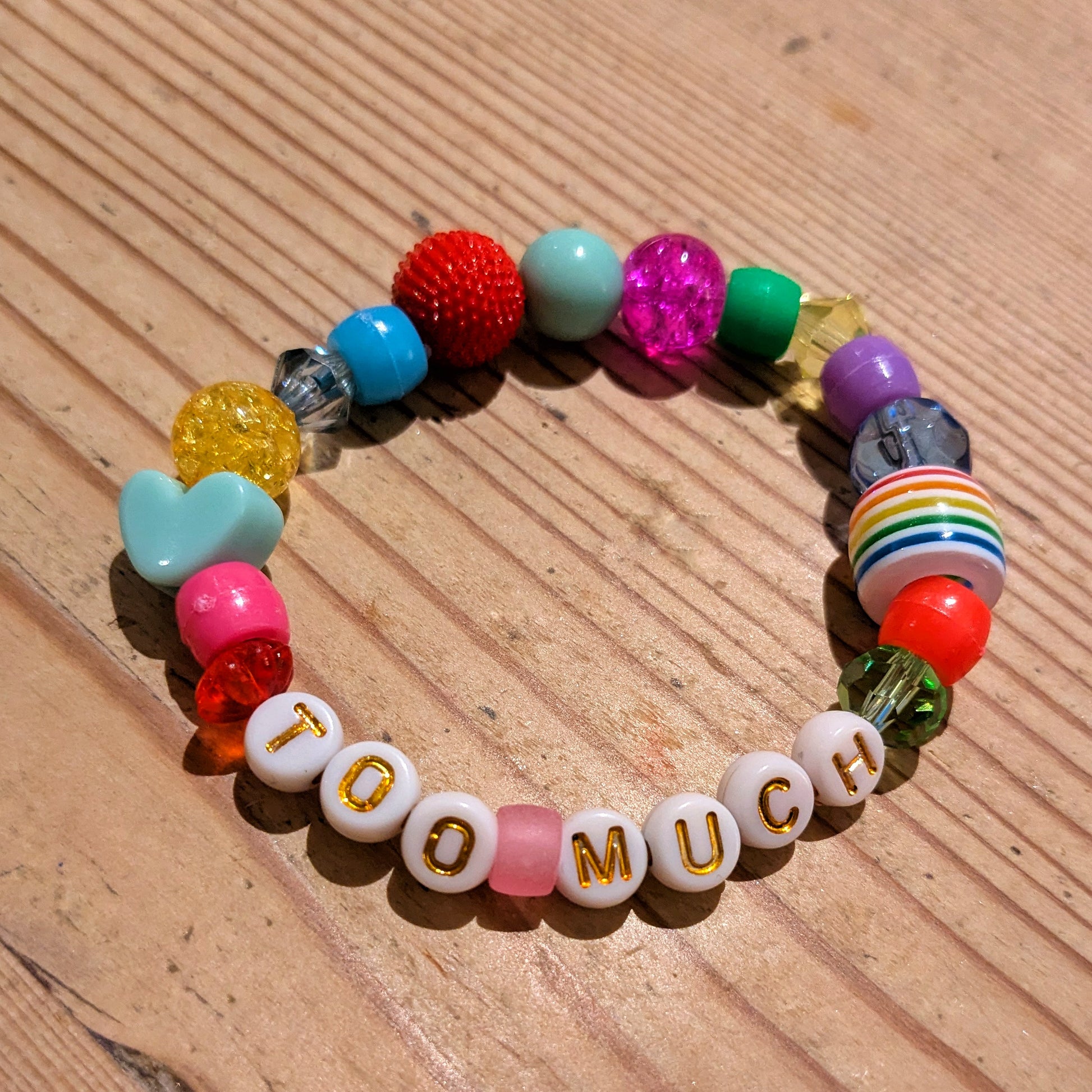 Friendship Bracelet with rainbow coloured beads and letter beads spelling Too Much