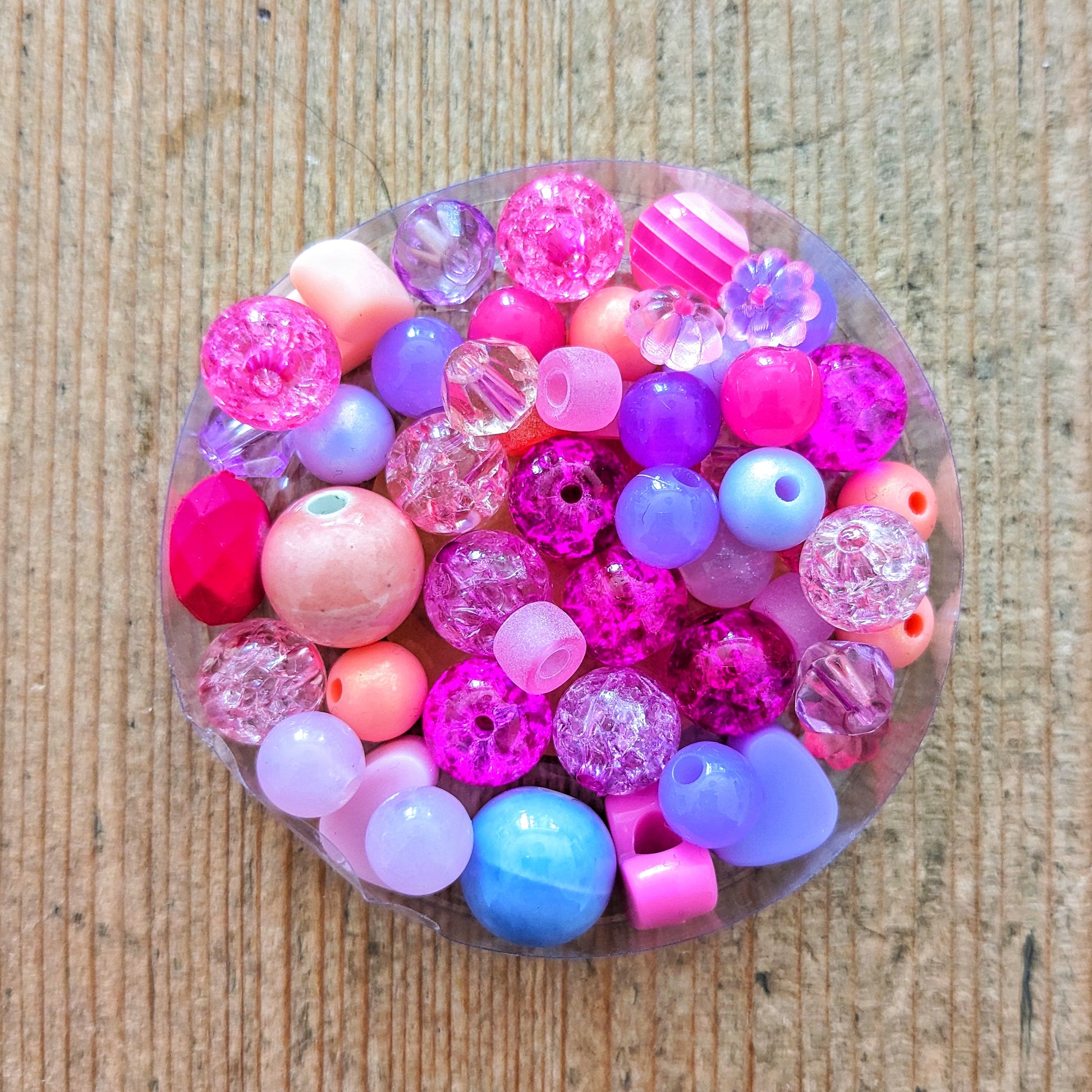 Variety of colourful glass and acrylic beads in pinks, peaches and purples