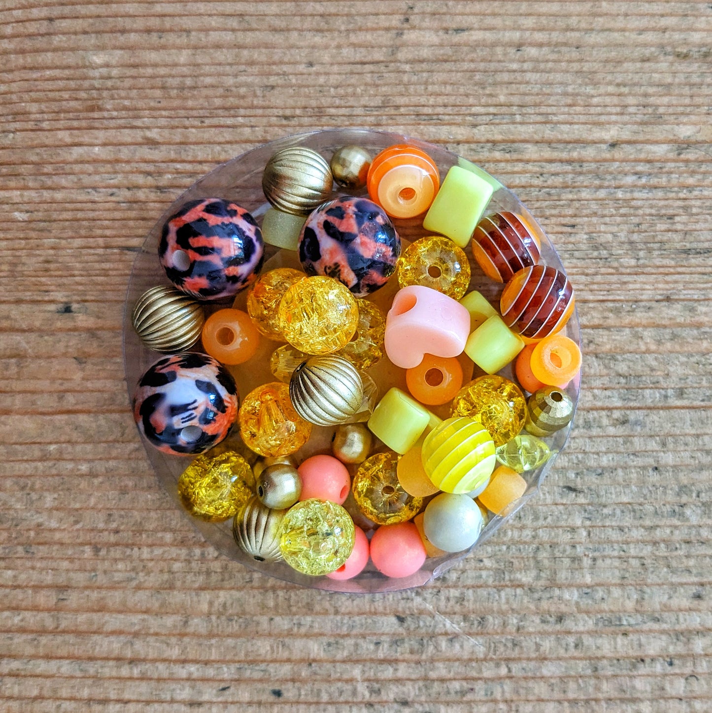 Variety of colourful glass and acrylic beads in orange and gold