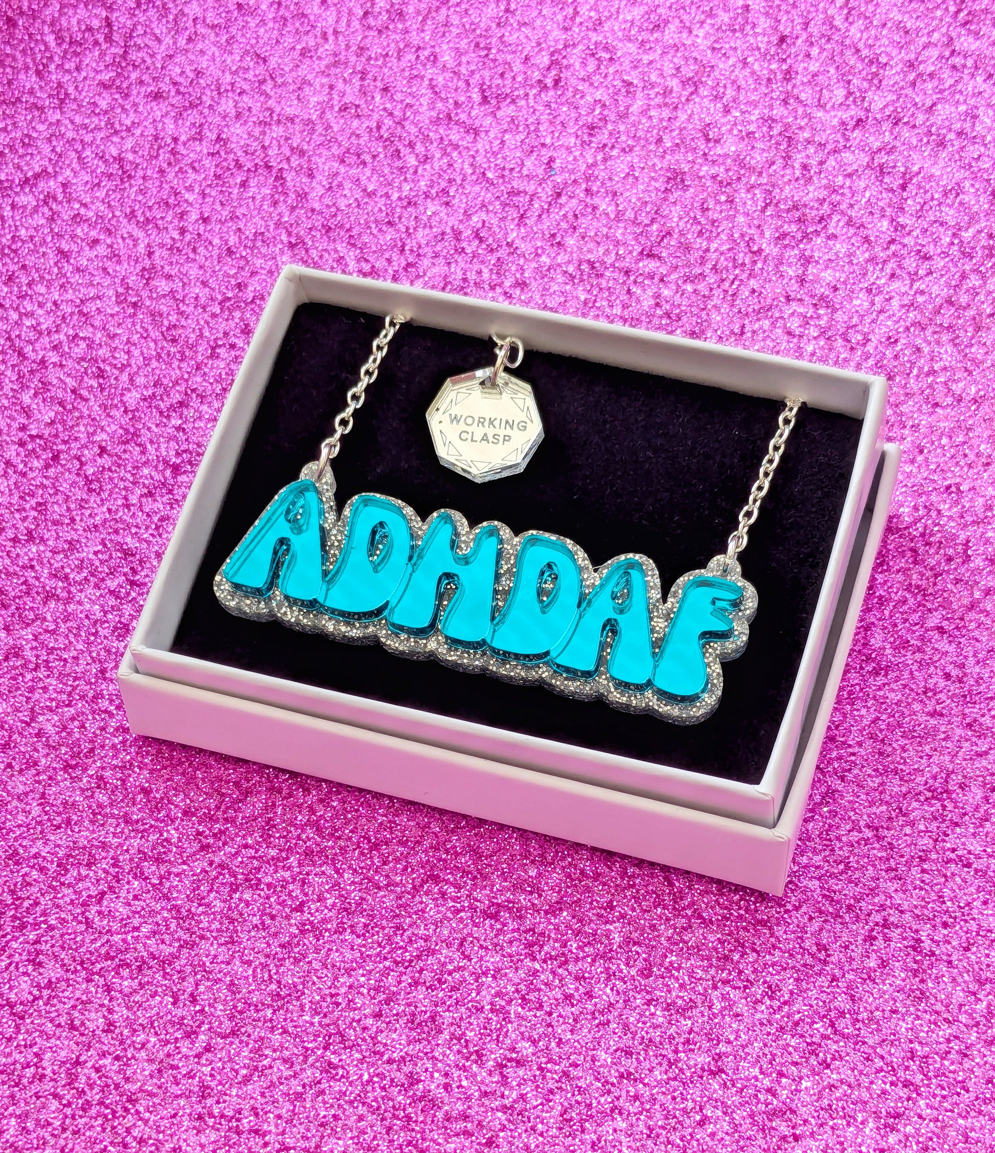 ADHDAF acrylic necklace in turquoise on silver chain boxed on a pink sparkly background